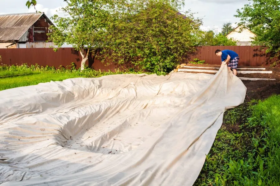 Lining a pond: protective underlay being laid across a pond excavation before the liner